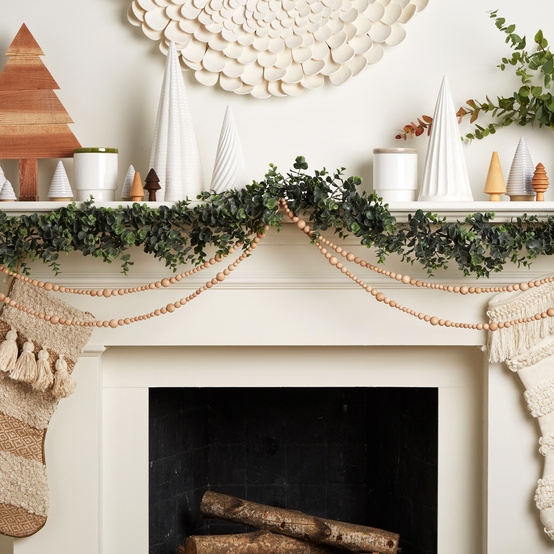 Scandinavian-inspired mantle white with wooden beaded garland greenery and trees