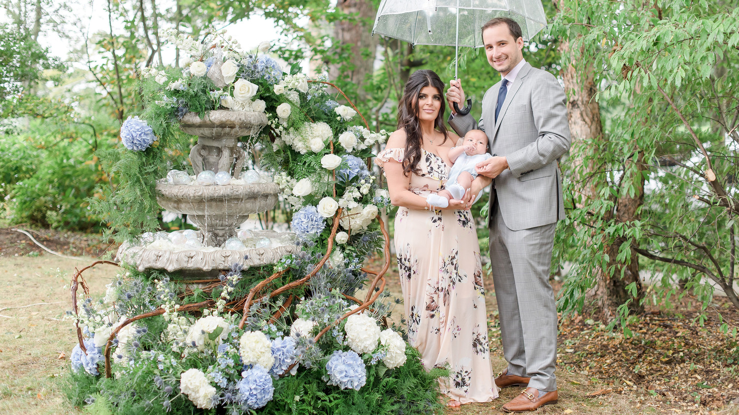 charitable baptism celebration couple with new baby by fountain and flowers