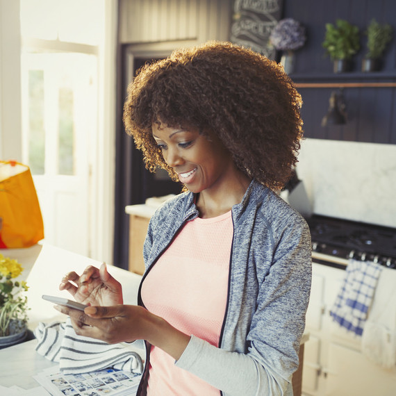 A woman smiles while looking at her cell phone. A woman smiles while looking at her cell phone.