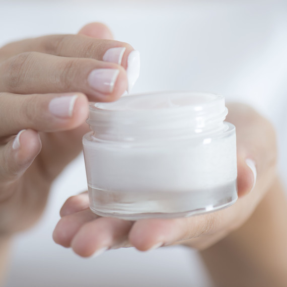 holding small bottle of skincare cream holding small bottle of skincare cream