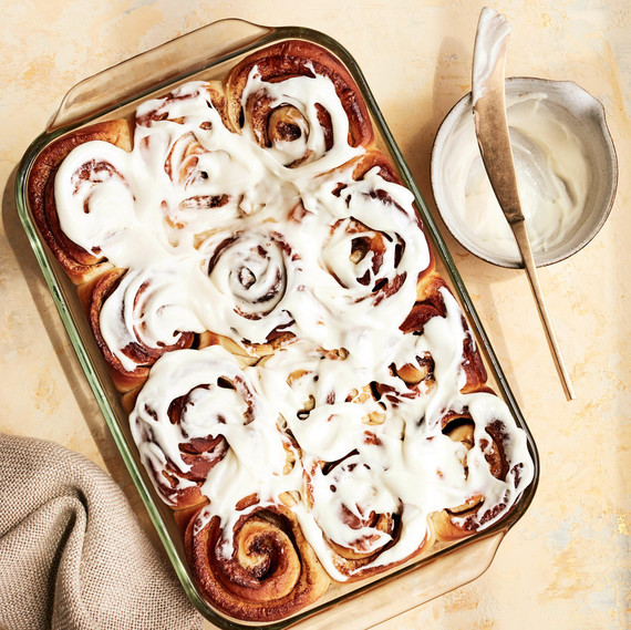 cinnamon rolls in glass pan with bowl of frosting cinnamon rolls in glass pan with bowl of frosting