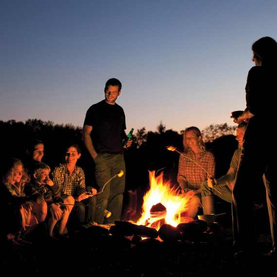 group of people sitting around campfire roasting marshmallows group of people sitting around campfire roasting marshmallows
