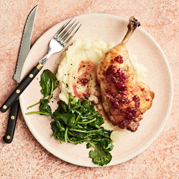 cranberry chicken with greens on plate with cutlery cranberry chicken with greens on plate with cutlery