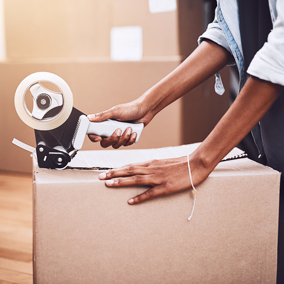 woman taping cardboard box woman taping cardboard box