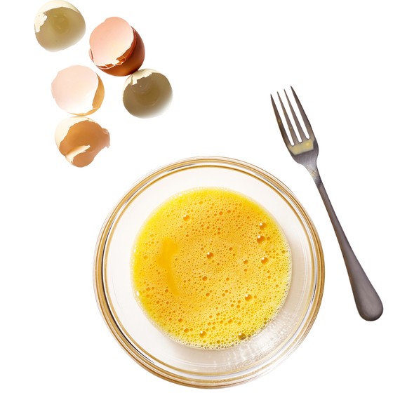 beaten egg in bowl next to fork beaten egg in bowl next to fork