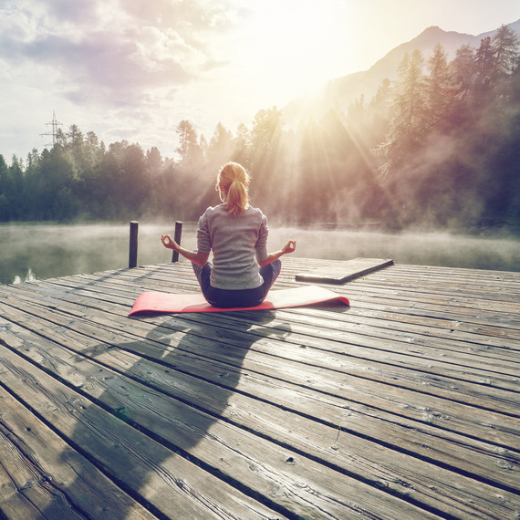 Woman Sitting on a Dock Doing Exercise in the Morning Woman Sitting on a Dock Doing Exercise in the Morning
