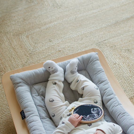 A baby holds an embroidery hoop with a sonogram embroidered on it. A baby holds an embroidery hoop with a sonogram embroidered on it.