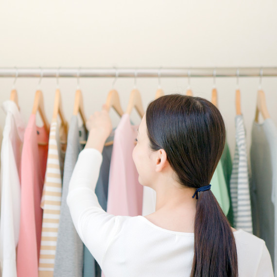 woman with ponytail looking through clothing rack woman with ponytail looking through clothing rack