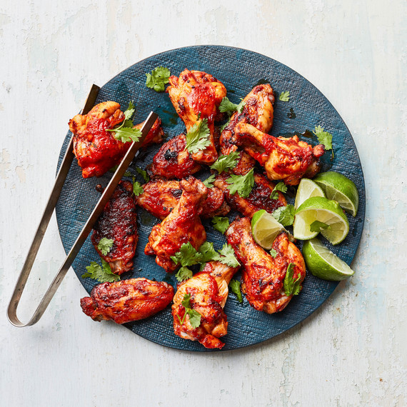 Quick Harissa Chicken Wings on blue board with tongs Quick Harissa Chicken Wings on blue board with tongs
