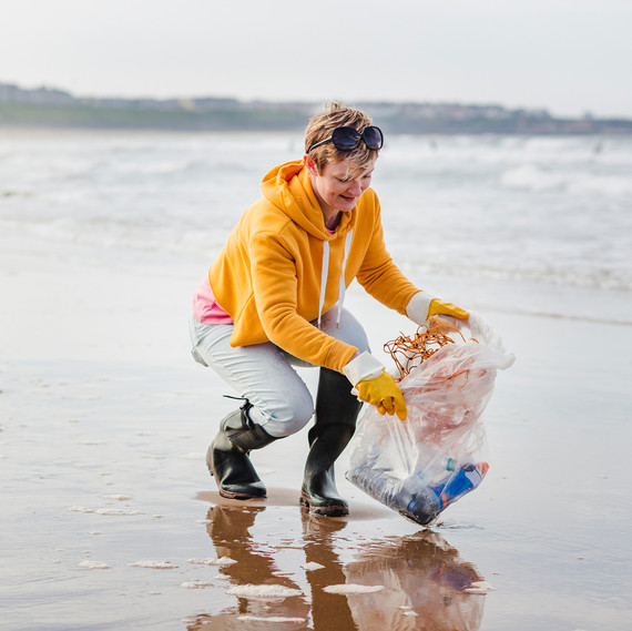 Woman Cleaning Trash of the Beach Shoreline Woman Cleaning Trash of the Beach Shoreline