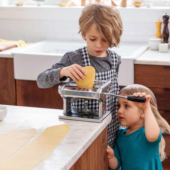 boy and girl hand-cranking pasta boy and girl hand-cranking pasta