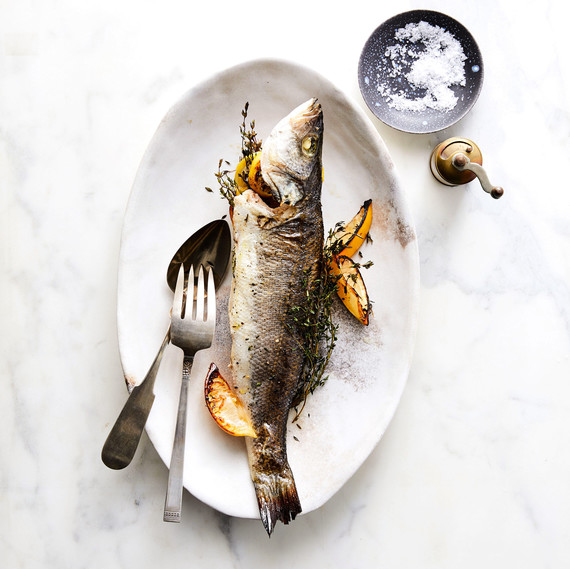 Whole-Roasted Branzino with Lemon and Thyme on plate with lemon wedges and silverware Whole-Roasted Branzino with Lemon and Thyme on plate with lemon wedges and silverware