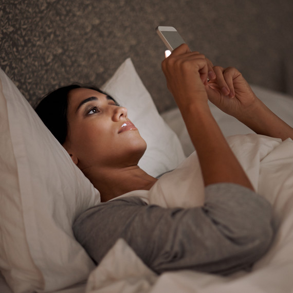 woman in bed looking at cell phone woman in bed looking at cell phone