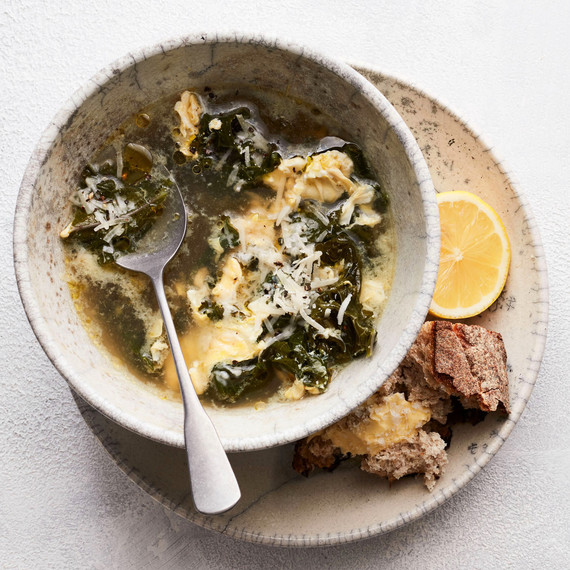 stracciatella soup with kale and lemon served in grey bowl with bread and lemon on the side stracciatella soup with kale and lemon served in grey bowl with bread and lemon on the side